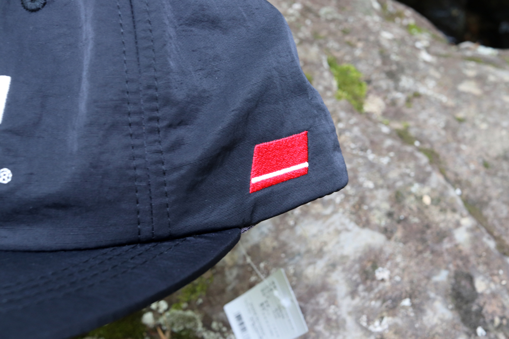 側面にフラッグ柄のワンポイント刺繍を施した、定番フラットバイザー キャップ。